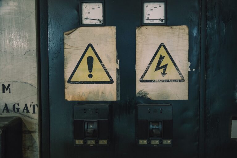 Zbliżenie na ostrzegawcze oznaczenia na zużytej tablicy elektrycznej